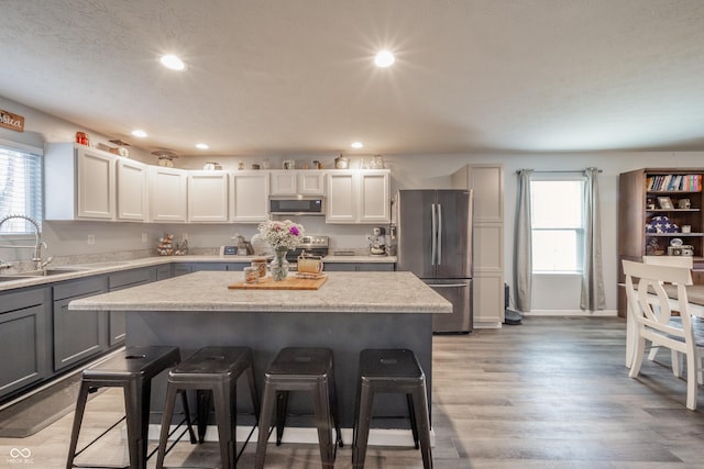 kitchen with sink, a center island, appliances with stainless steel finishes, a kitchen breakfast bar, and plenty of natural light