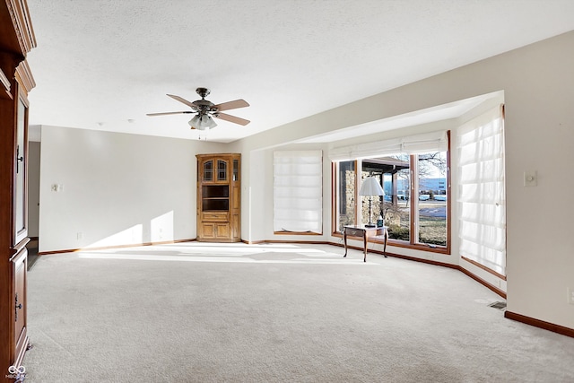 unfurnished living room with light carpet, ceiling fan, and a textured ceiling