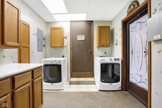 washroom with cabinets, washing machine and clothes dryer, and electric panel