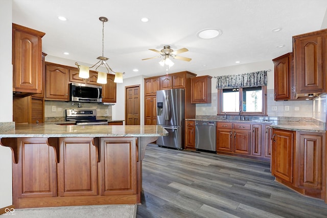 kitchen featuring pendant lighting, a breakfast bar area, kitchen peninsula, stainless steel appliances, and dark wood-type flooring