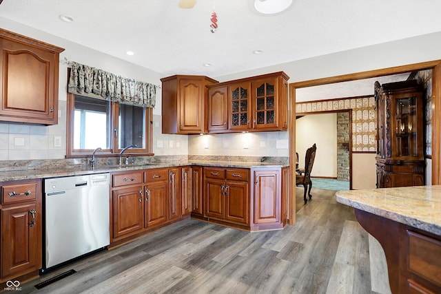 kitchen featuring hardwood / wood-style flooring, dishwasher, sink, and light stone countertops