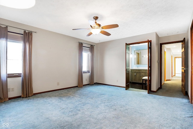 unfurnished bedroom featuring ensuite bathroom, light carpet, ceiling fan, and a textured ceiling