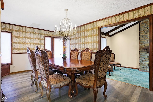 dining room featuring an inviting chandelier, vaulted ceiling, a textured ceiling, ornamental molding, and hardwood / wood-style flooring