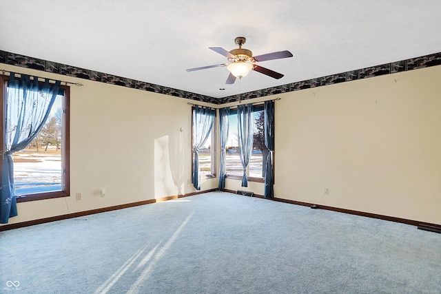 carpeted spare room with ceiling fan and plenty of natural light