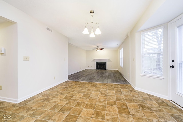 unfurnished living room featuring ceiling fan with notable chandelier