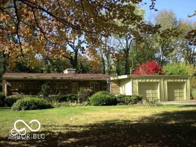 mid-century home featuring a garage and a front yard