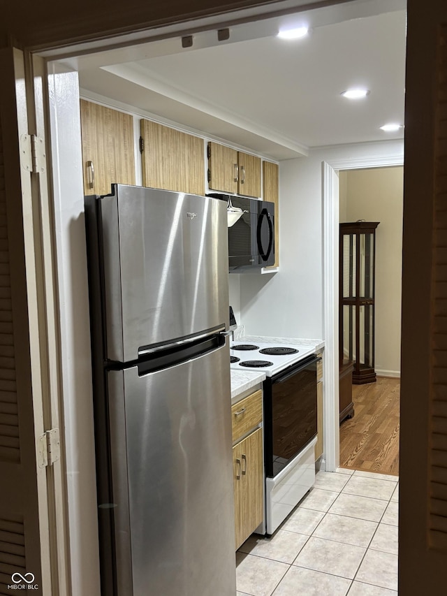 kitchen featuring stainless steel refrigerator, light brown cabinetry, light tile patterned flooring, and range with electric cooktop