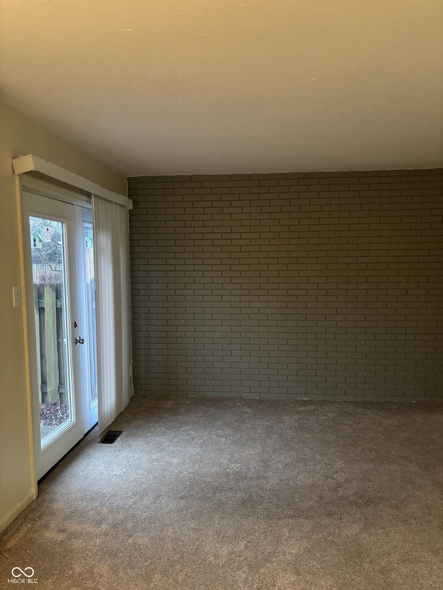 spare room with brick wall and carpet floors