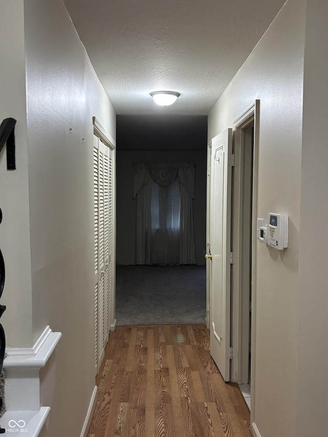 hall with hardwood / wood-style flooring and a textured ceiling