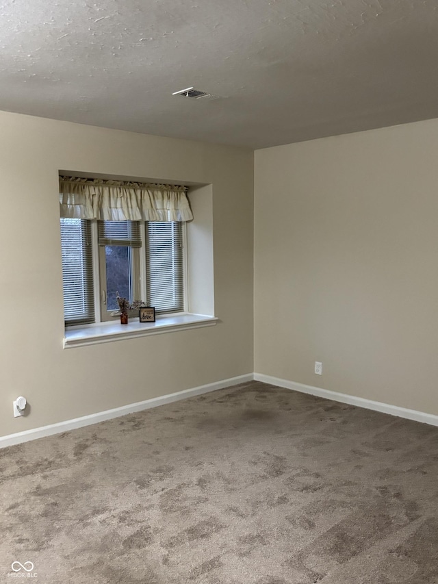 carpeted spare room with a textured ceiling