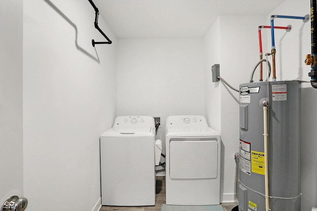 clothes washing area featuring hardwood / wood-style flooring, washing machine and dryer, and electric water heater