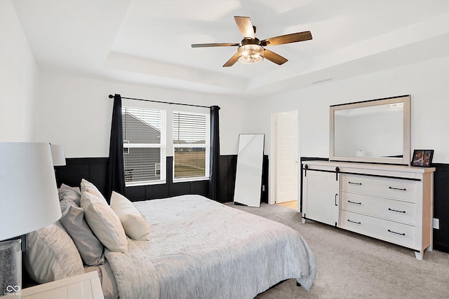 carpeted bedroom featuring a raised ceiling and ceiling fan