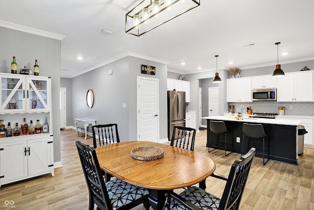 dining room featuring ornamental molding, sink, and light hardwood / wood-style floors