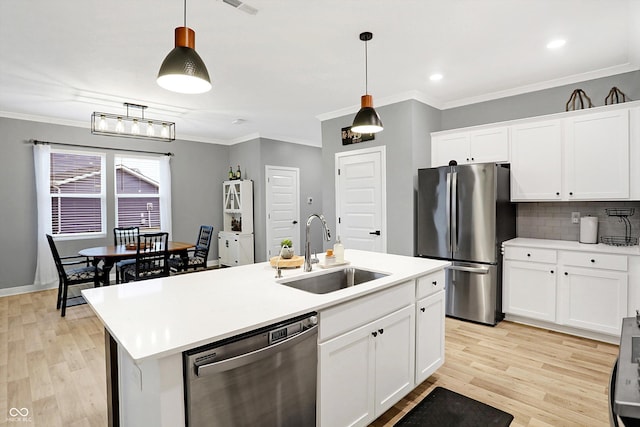 kitchen featuring sink, white cabinetry, appliances with stainless steel finishes, an island with sink, and pendant lighting