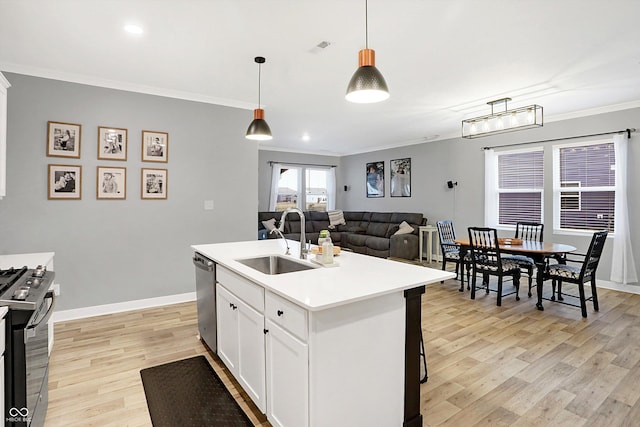 kitchen featuring range with gas stovetop, sink, white cabinets, hanging light fixtures, and a center island with sink