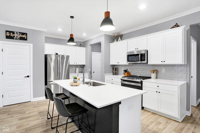 kitchen with pendant lighting, an island with sink, sink, white cabinets, and stainless steel appliances