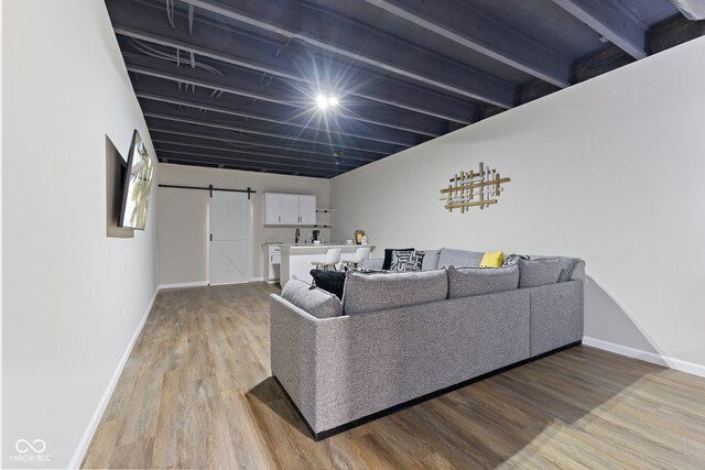 living area featuring light wood-style flooring, baseboards, and a barn door