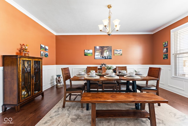 dining room with ornamental molding, a notable chandelier, a decorative wall, and wood finished floors