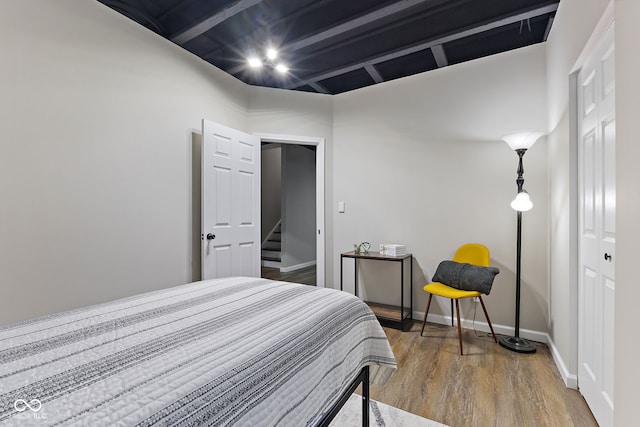 bedroom featuring vaulted ceiling with beams, baseboards, and wood finished floors