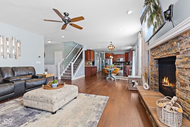 living area with recessed lighting, stairs, dark wood-type flooring, and a stone fireplace