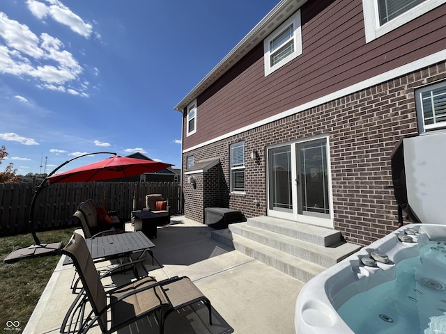 view of patio featuring entry steps, fence, and a hot tub