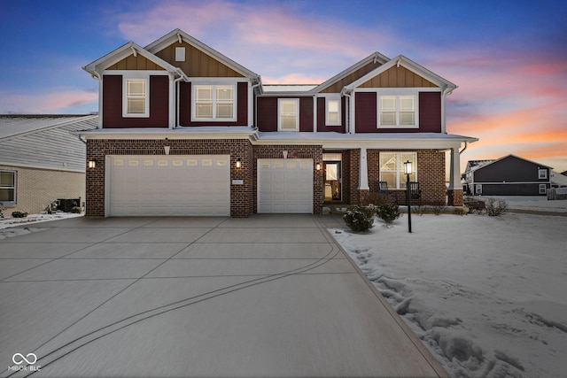 view of front facade with a garage, driveway, brick siding, and board and batten siding