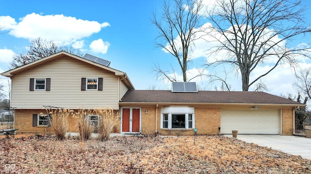 tri-level home featuring a garage, brick siding, and driveway