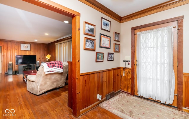 entryway featuring visible vents, a wainscoted wall, wood finished floors, crown molding, and wood walls