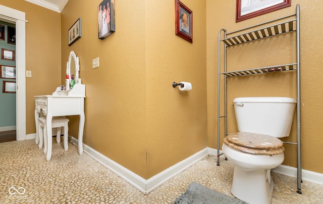 bathroom with crown molding, toilet, and baseboards