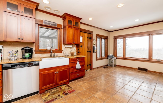 kitchen with visible vents, glass insert cabinets, light stone countertops, stainless steel dishwasher, and a sink