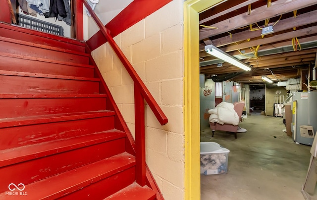 stairway featuring water heater and unfinished concrete floors