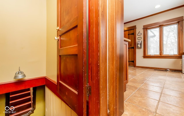 hall featuring ornamental molding, light tile patterned flooring, and baseboards