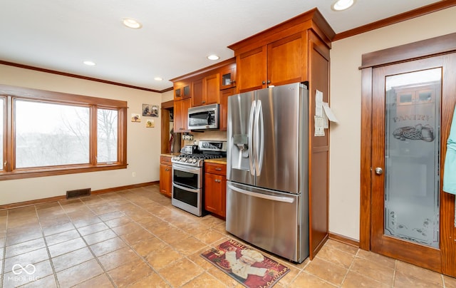 kitchen with visible vents, brown cabinetry, glass insert cabinets, ornamental molding, and stainless steel appliances