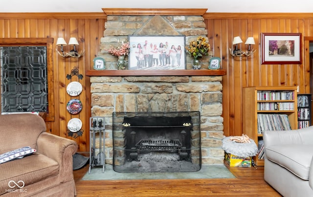 living room featuring wooden walls, a stone fireplace, and wood finished floors