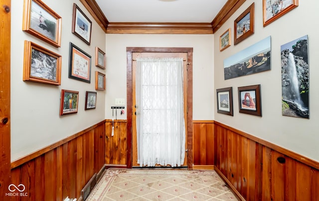 doorway to outside with ornamental molding, wood walls, and wainscoting