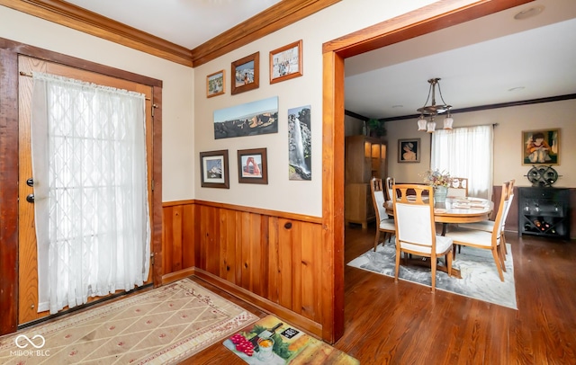 dining space with ornamental molding, a wainscoted wall, dark wood finished floors, and wood walls