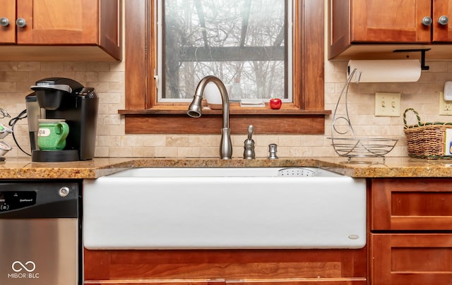 kitchen featuring light stone countertops, a sink, stainless steel dishwasher, decorative backsplash, and brown cabinets