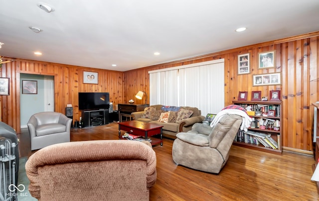 living area with wooden walls, wood finished floors, and recessed lighting