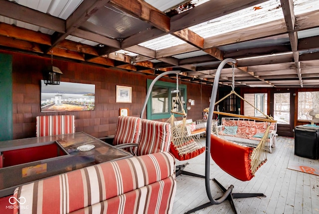 interior space featuring concrete block wall, coffered ceiling, wood finished floors, and beamed ceiling