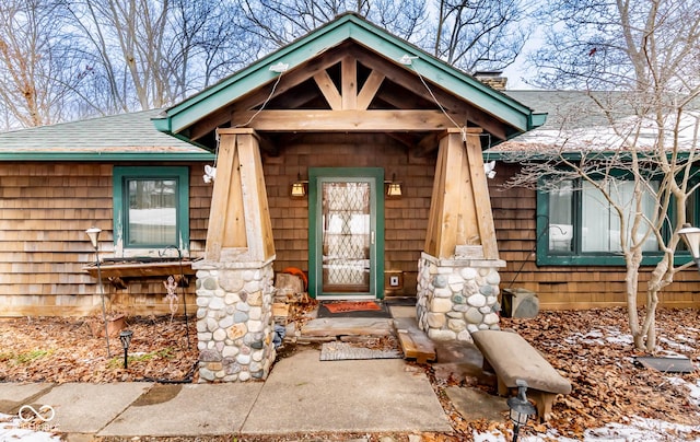 doorway to property with roof with shingles and a chimney