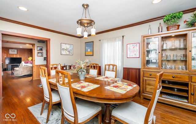 dining area featuring a wainscoted wall, dark wood-style flooring, crown molding, a notable chandelier, and recessed lighting