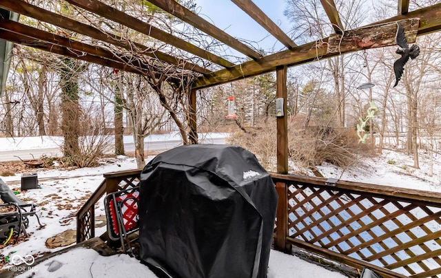 snow covered deck featuring area for grilling and a pergola