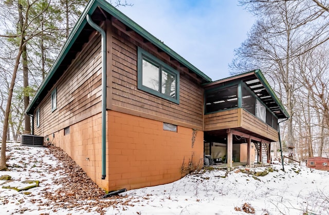 view of snow covered exterior featuring stairway, a sunroom, and central air condition unit