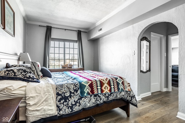 bedroom featuring a textured ceiling, wood finished floors, crown molding, and a textured wall