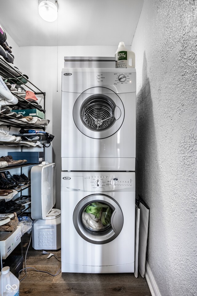 laundry room with a textured wall, dark wood finished floors, and stacked washer and clothes dryer