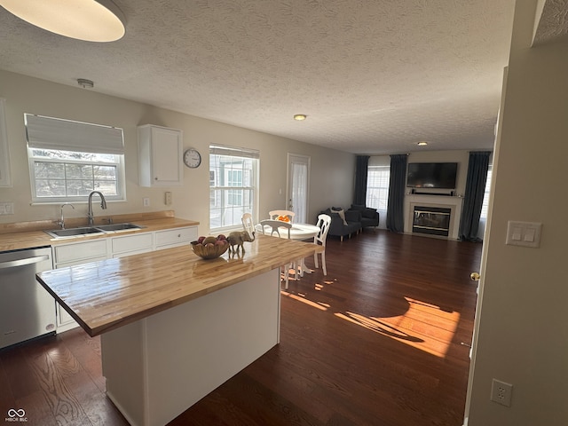 kitchen featuring sink, white cabinetry, wooden counters, stainless steel dishwasher, and a kitchen island