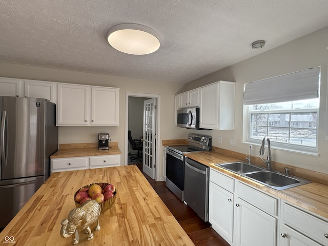 kitchen featuring sink, stainless steel appliances, wooden counters, and white cabinets