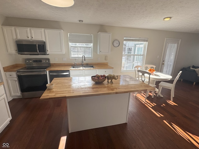 kitchen featuring butcher block countertops, sink, white cabinets, a center island, and stainless steel appliances