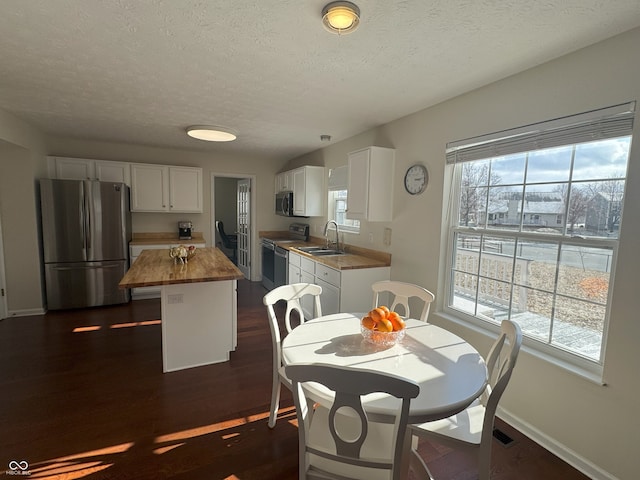 dining area featuring sink, a wealth of natural light, a textured ceiling, and dark hardwood / wood-style floors