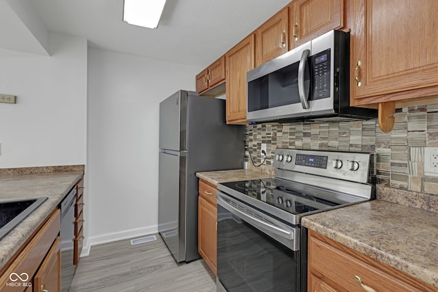 kitchen featuring backsplash, stainless steel appliances, and light wood-type flooring